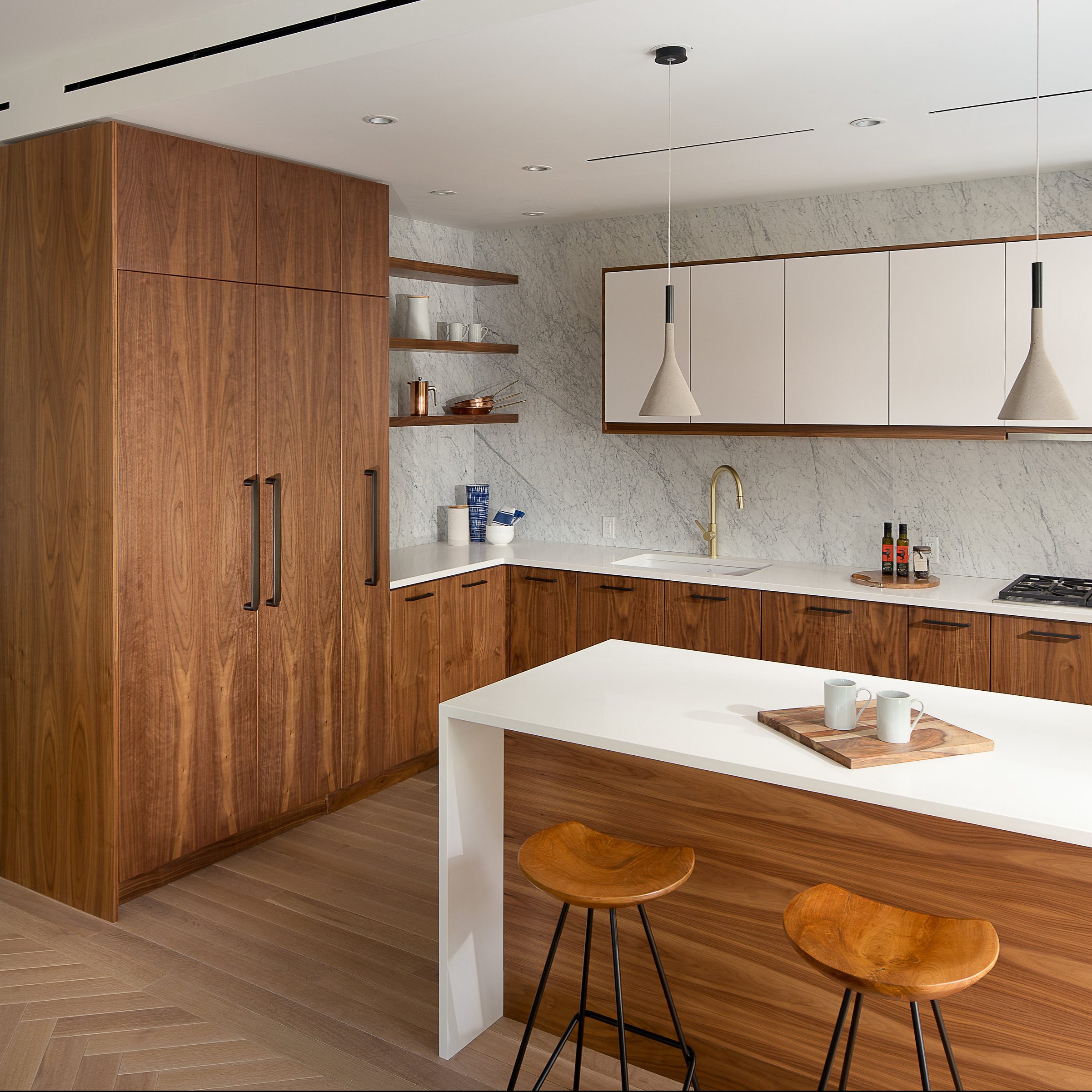 Modern kitchen with wooden cabinets, white countertops, hanging pendant lights, and bar stools by an island, ideal for home remodeling.