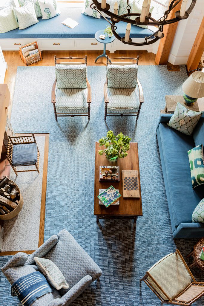 Cozy living room with two sofas, two chairs, a wooden coffee table, blue rug, and Maine-inspired nautical decor, viewed from above.
