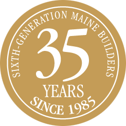 Round gold seal with text "sixth-generation Maine home builders, 35 years since 1985" celebrating a business milestone in Wells.
