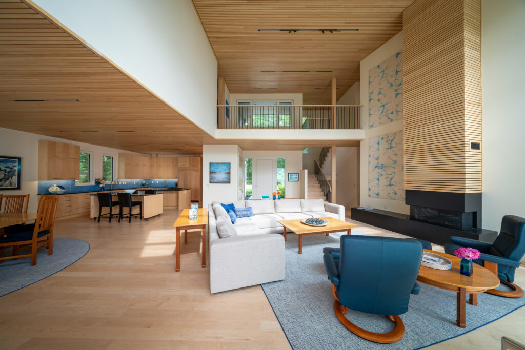 Modern living room with high ceilings, wooden accents, a blue and white color scheme, custom homes-inspired design, and multiple seating areas.