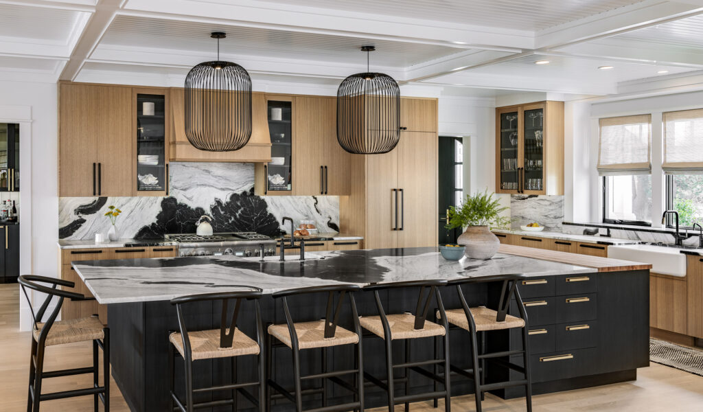 Modern kitchen with black and wooden cabinetry, marble countertops, and woven pendant lights over a central island with bar stools, recently upgraded during custom home renovations.